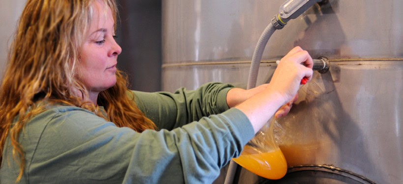 Woman pouring wine into a glass from a stainless steel tank at D'Alfonso-Curran Wines.
